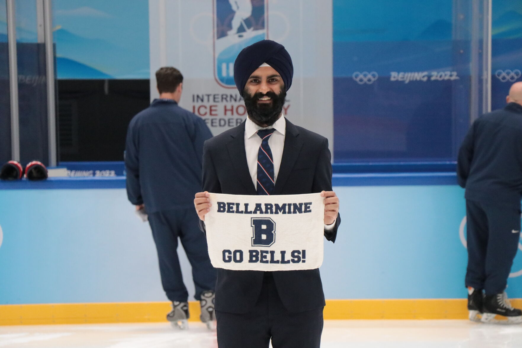 Brij Singh on the ice at the Bejing 2022 Winter Olympics while holding a rally towel in honor of his high school Bellarmine College Preparatory school in San Jose.
