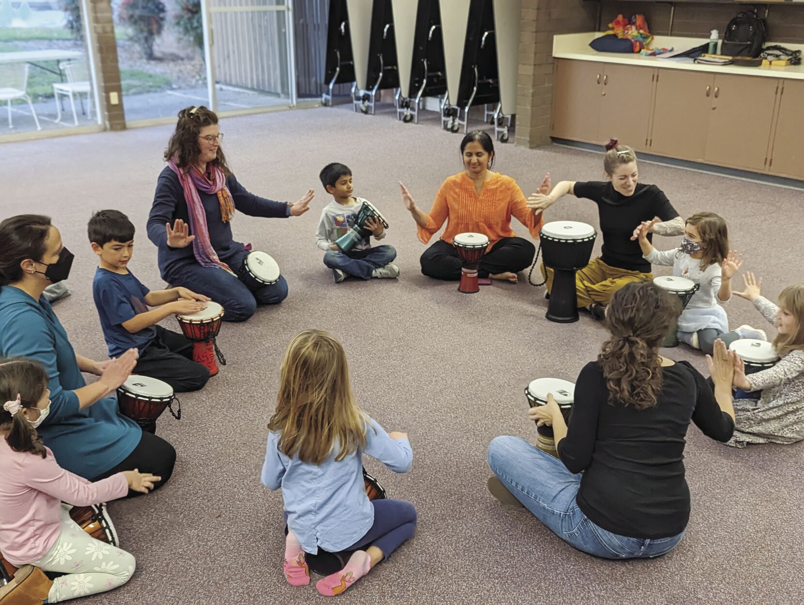 Rizzie Vacketta, with largest drum, leads families in a Rhythm Kids version of the Music Together class, which introduces patterns on the djembe drum.