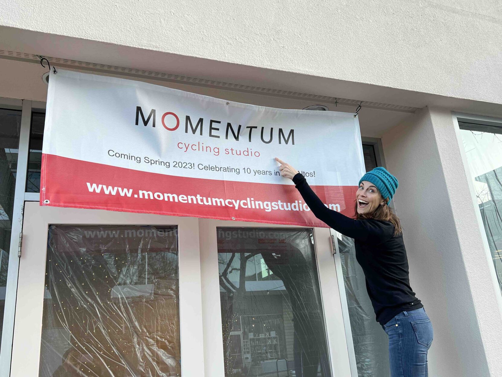 Momentum Cycling Studio owner Victoria Sommers hangs a sign above the front door of what will soon be her new location on State Street.